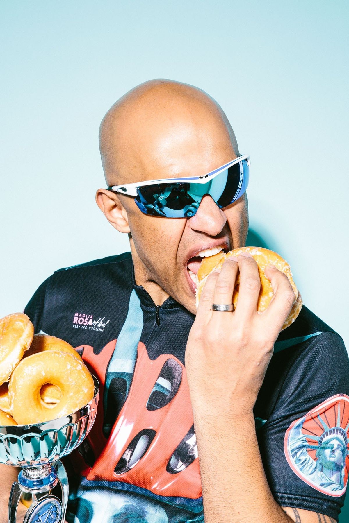 Yasir Salem in wraparound sunglasses biting a donut, trophy of donuts in hand